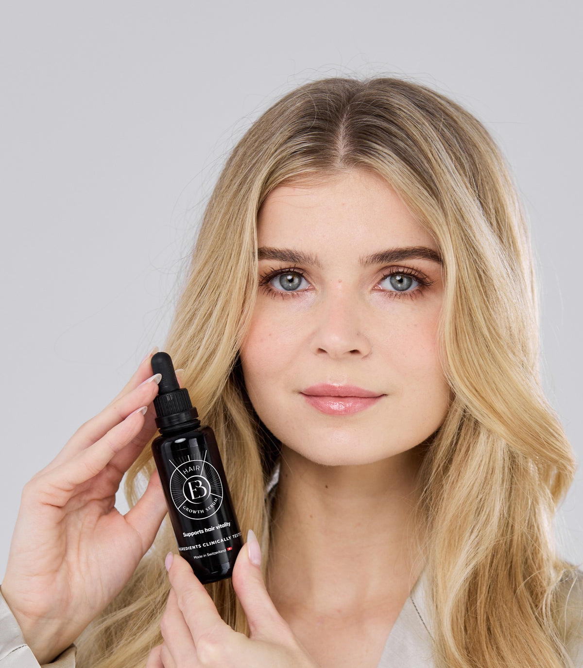 Flacon Hair Growth Serum tenu près du visage