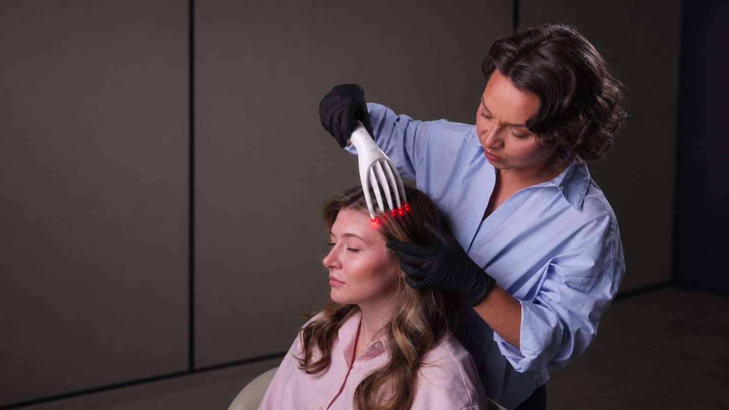 Le peigne LED à lumière rouge sur le cuir chevelu d’une cliente