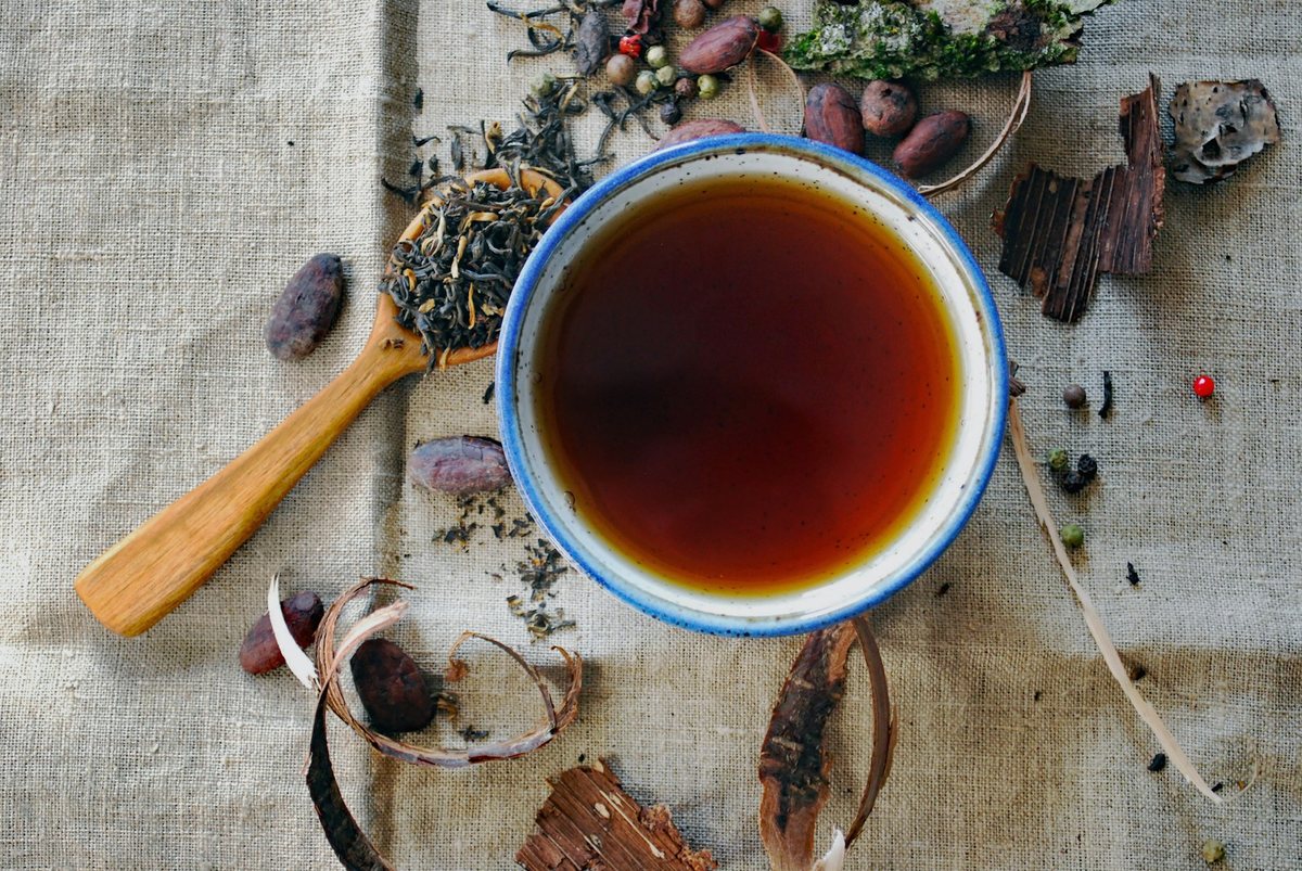 Un bol de tisane sur une nappe de lin, entouré d’épices
