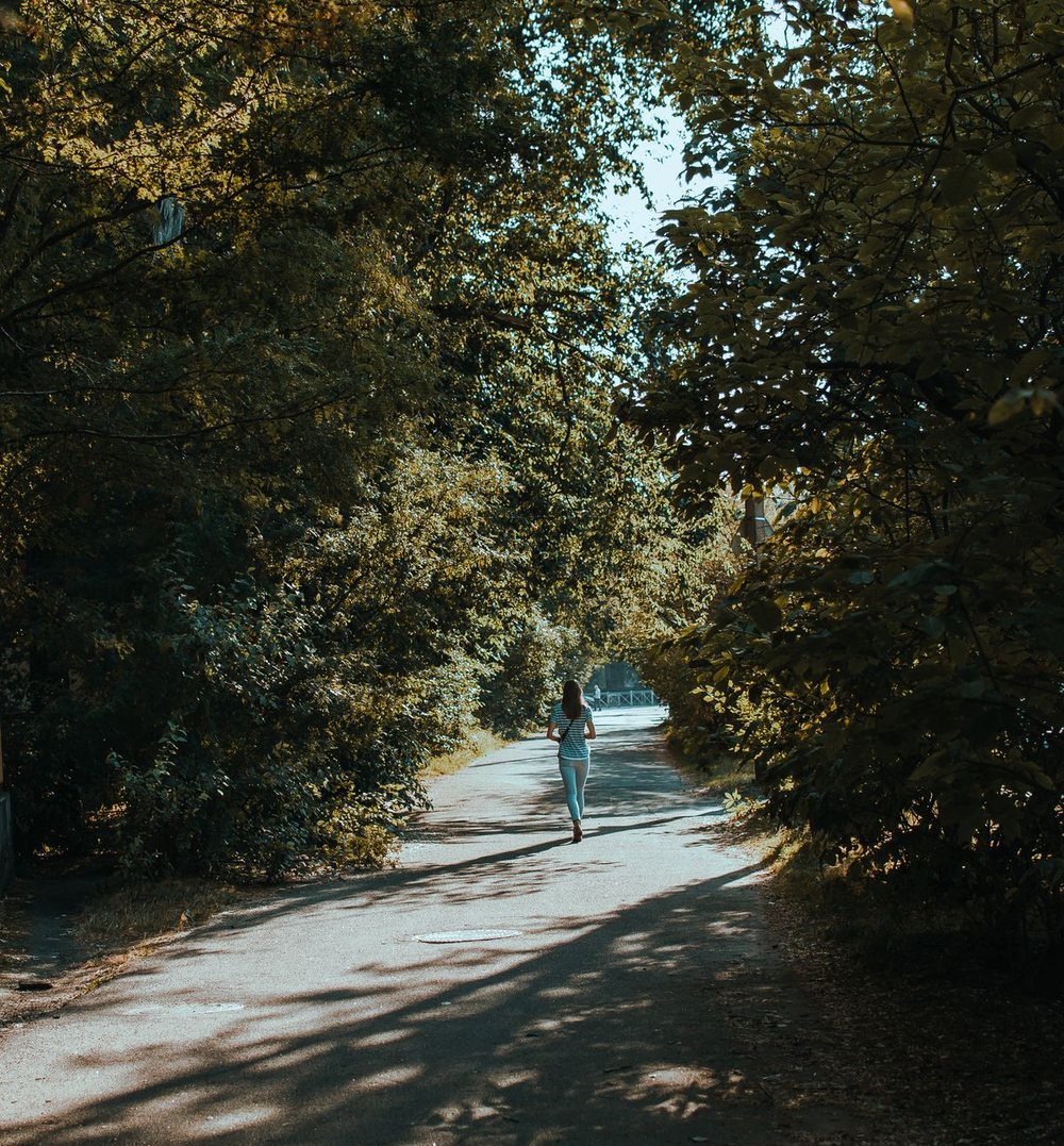 Une femme qui court sur un chemin bordé d’arbres