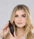 Flacon Hair Growth Serum tenu près du visage
